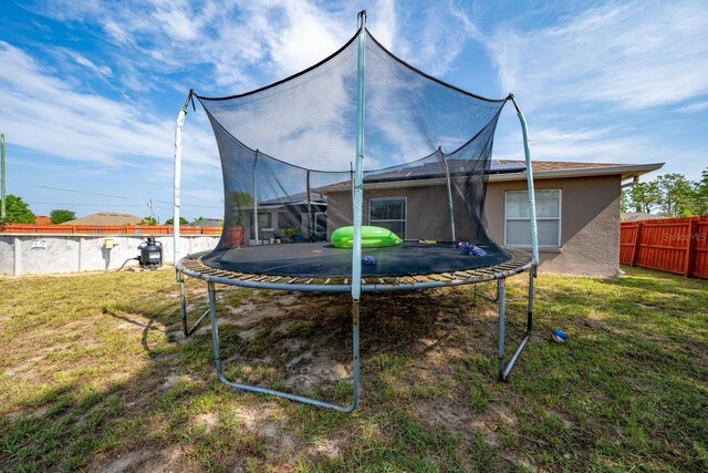 402 Ohio Way, Kissimmee, FL 34759 - back of house with a trampoline and stucco siding