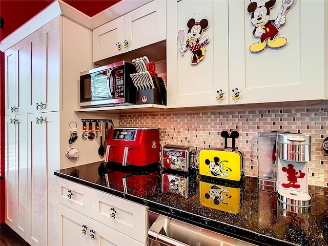 550 Canary Island Cir, Davenport, FL 33837 - kitchen with stainless steel microwave, decorative backsplash, and white cabinetry