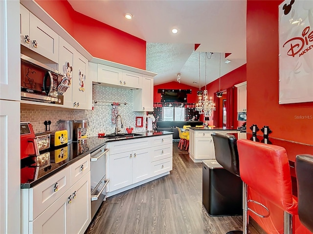 550 Canary Island Cir, Davenport, FL 33837 - kitchen with a sink, vaulted ceiling, stainless steel appliances, white cabinets, and dark countertops
