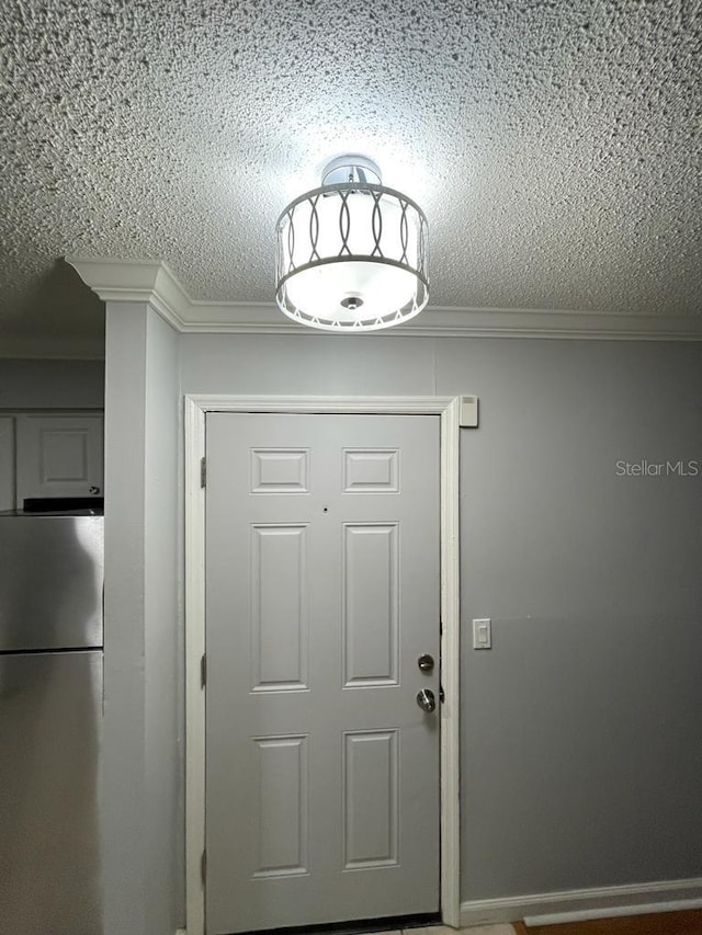 entryway featuring a textured ceiling and ornamental molding