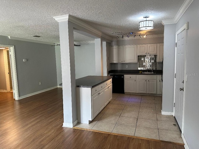 kitchen featuring black dishwasher, track lighting, ornamental molding, dark countertops, and a textured ceiling