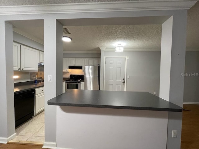 kitchen with appliances with stainless steel finishes, crown molding, dark countertops, white cabinets, and under cabinet range hood