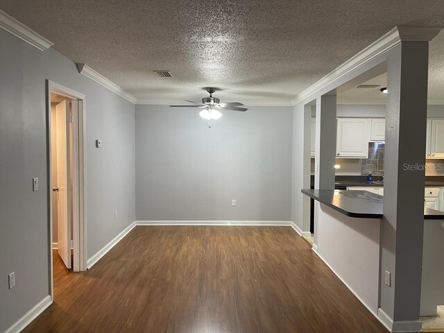 unfurnished room with ceiling fan, dark wood-style flooring, crown molding, a textured ceiling, and baseboards