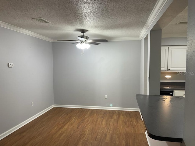 unfurnished dining area featuring dark wood finished floors, ornamental molding, a textured ceiling, a ceiling fan, and baseboards