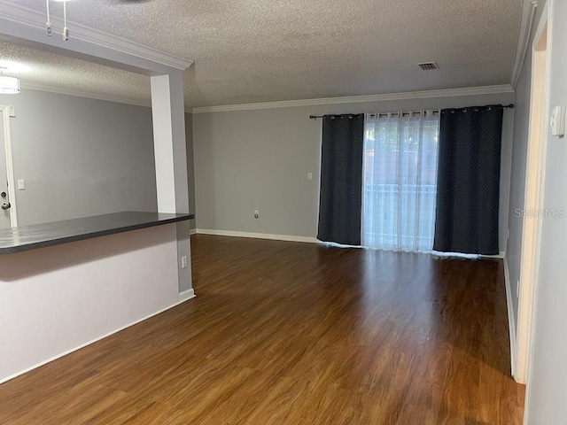 unfurnished room featuring a textured ceiling, ornamental molding, dark wood-style floors, and baseboards