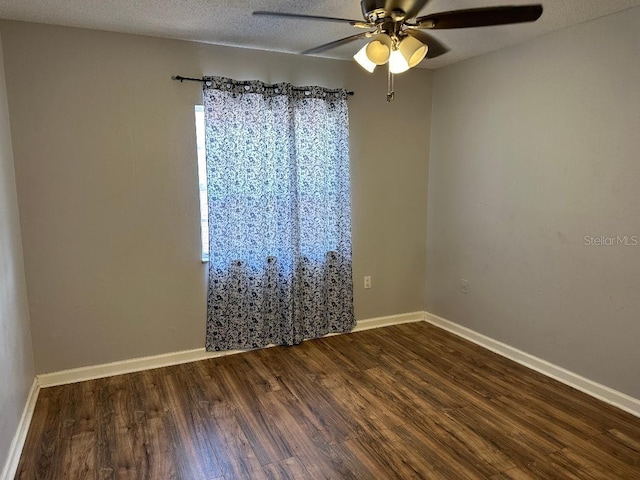 spare room featuring dark wood-style flooring, ceiling fan, and baseboards