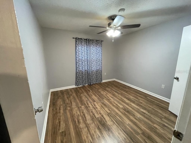 unfurnished room featuring dark wood finished floors, ceiling fan, baseboards, and a textured ceiling