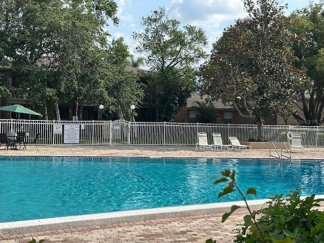 community pool featuring fence and a patio area