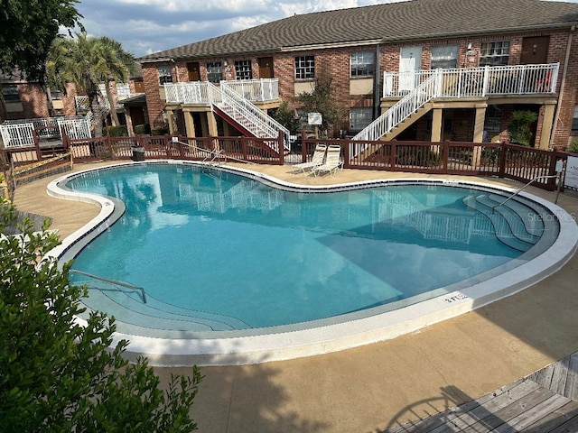 community pool with stairs and a deck
