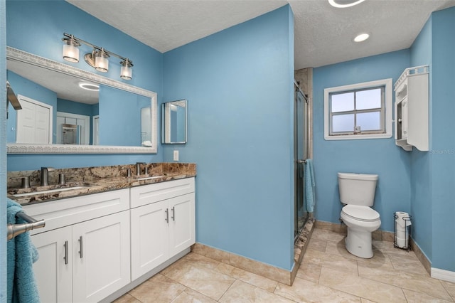 full bathroom with baseboards, a stall shower, a textured ceiling, toilet, and double vanity