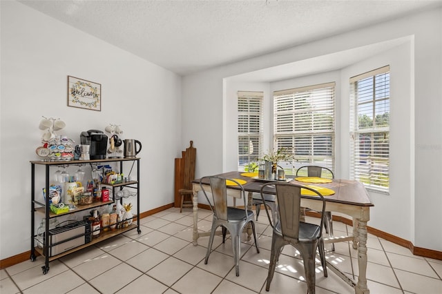 dining room featuring baseboards, a textured ceiling, and light tile patterned flooring