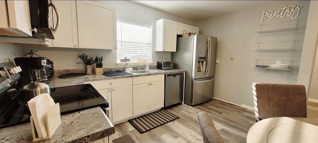 2729 Club Cortile Cir, Kissimmee, FL 34746 - kitchen with appliances with stainless steel finishes, light wood-style flooring, white cabinets, and a sink