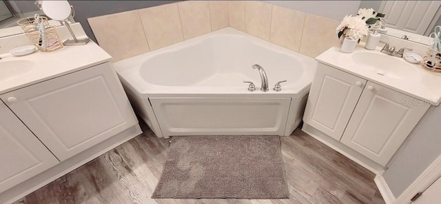 2729 Club Cortile Cir, Kissimmee, FL 34746 - bathroom featuring wood finished floors, a bath, and two vanities