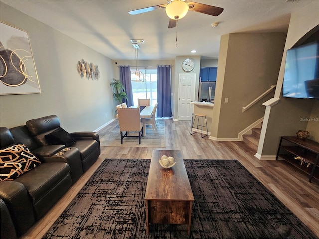 2531 Old Kent Cir, Kissimmee, FL 34758 - living area with light wood-style flooring, ceiling fan, stairway, and baseboards