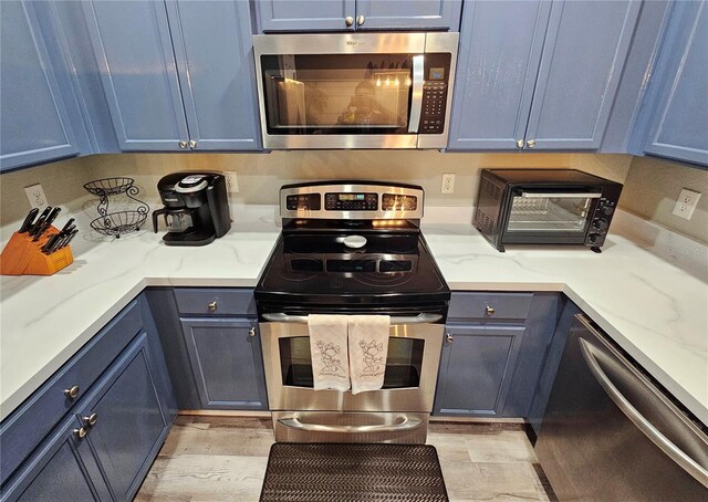 2531 Old Kent Cir, Kissimmee, FL 34758 - kitchen featuring stainless steel appliances, blue cabinetry, and light stone counters