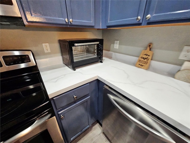 2531 Old Kent Cir, Kissimmee, FL 34758 - kitchen featuring stainless steel appliances, blue cabinets, and light stone countertops