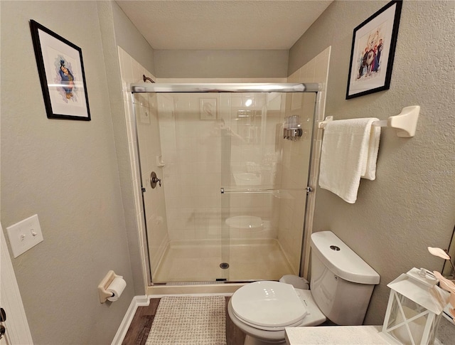 2531 Old Kent Cir, Kissimmee, FL 34758 - bathroom with toilet, a shower stall, a textured wall, a textured ceiling, and baseboards