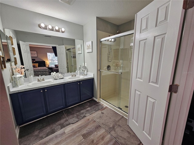 2531 Old Kent Cir, Kissimmee, FL 34758 - ensuite bathroom featuring wood finished floors, double vanity, a shower stall, and a textured ceiling