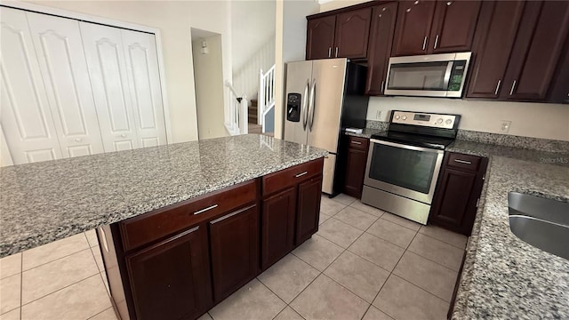 979 Hacienda Cir, Kissimmee, FL 34741 - kitchen featuring appliances with stainless steel finishes, light tile patterned floors, light stone counters, and dark brown cabinets