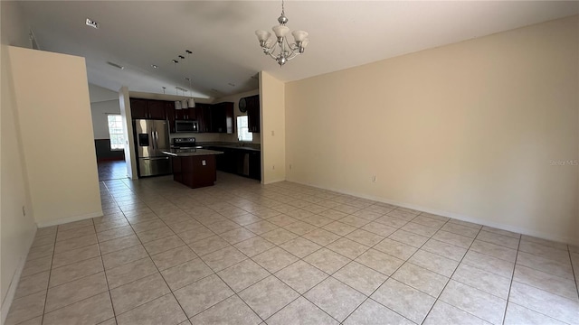 979 Hacienda Cir, Kissimmee, FL 34741 - kitchen with stainless steel appliances, open floor plan, vaulted ceiling, light tile patterned flooring, and a chandelier