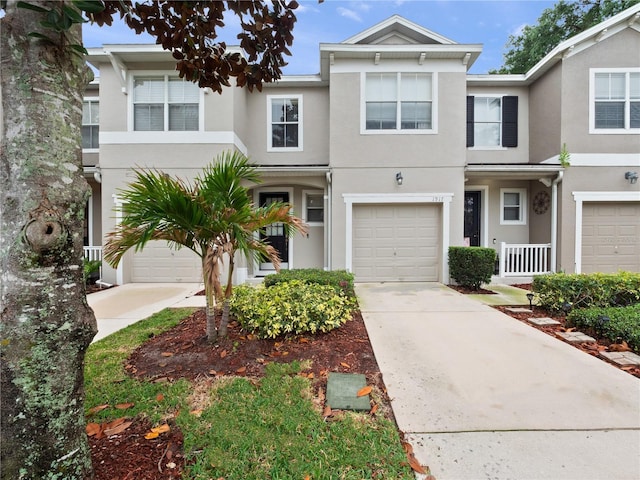 townhome / multi-family property with stucco siding, driveway, and an attached garage