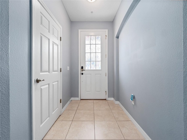 doorway to outside with light tile patterned flooring and baseboards
