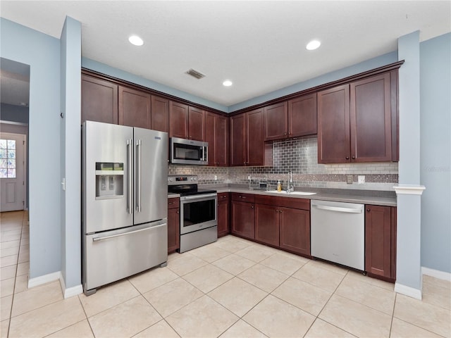 kitchen featuring stainless steel appliances, a sink, backsplash, light tile patterned floors, and recessed lighting