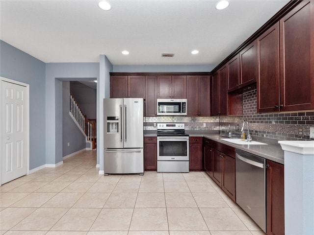 kitchen featuring stainless steel appliances, a sink, backsplash, light tile patterned floors, and recessed lighting