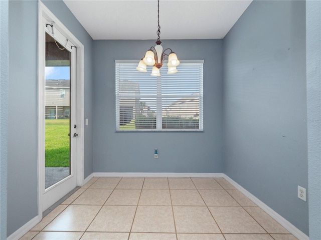 unfurnished dining area featuring a chandelier, healthy amount of natural light, light tile patterned flooring, and baseboards