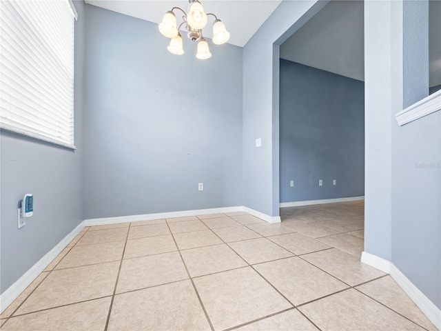 unfurnished room with a chandelier, tile patterned floors, and baseboards