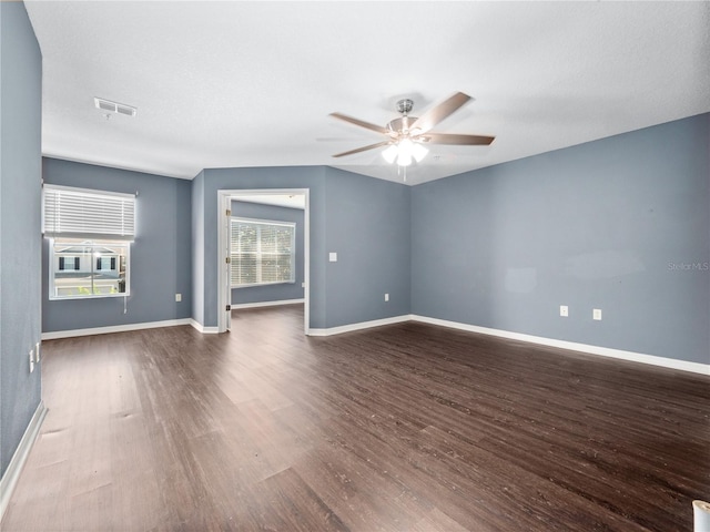 unfurnished room featuring dark wood finished floors, a ceiling fan, and baseboards