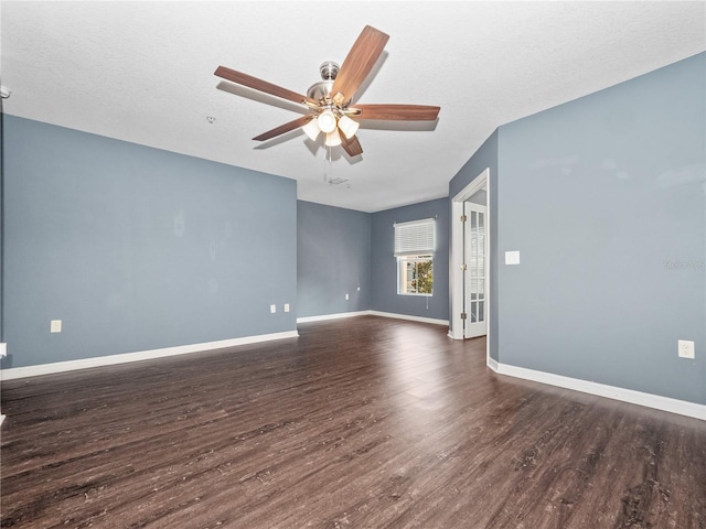 spare room with dark wood-type flooring, a ceiling fan, baseboards, and a textured ceiling