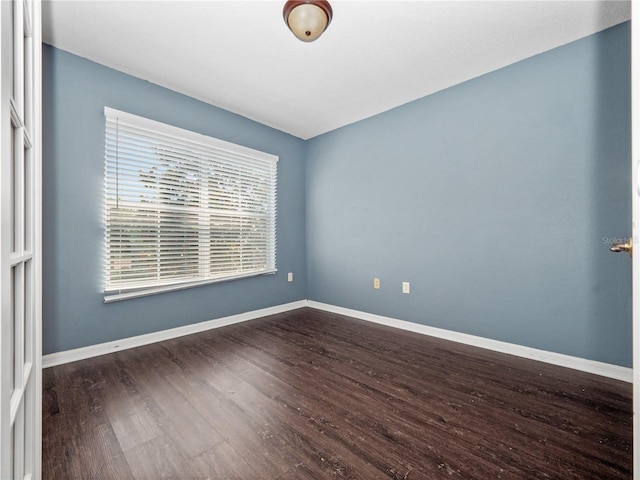 spare room featuring dark wood-style flooring and baseboards