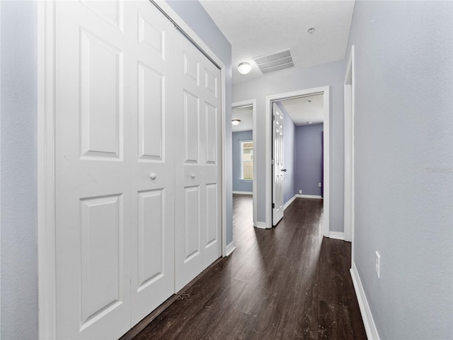 hall with dark wood-style flooring and baseboards