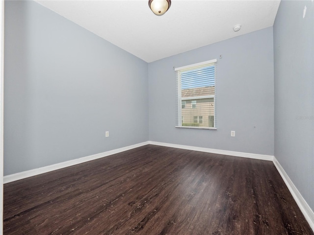 empty room with dark wood-style flooring, baseboards, lofted ceiling, and a smoke detector