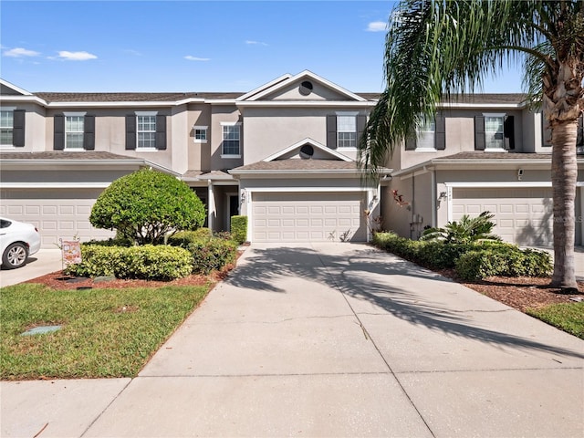 townhome / multi-family property with stucco siding, driveway, and a garage
