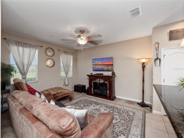living area featuring a ceiling fan, a fireplace, light tile patterned floors, and baseboards