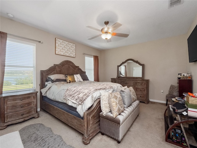 bedroom featuring multiple windows, light colored carpet, baseboards, and a ceiling fan