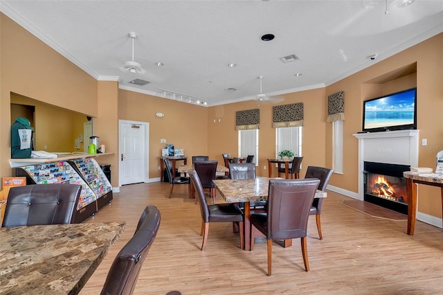 8571 La Isla Dr, Kissimmee, FL 34747 - dining room featuring ornamental molding, light wood-style flooring, a glass covered fireplace, and a ceiling fan