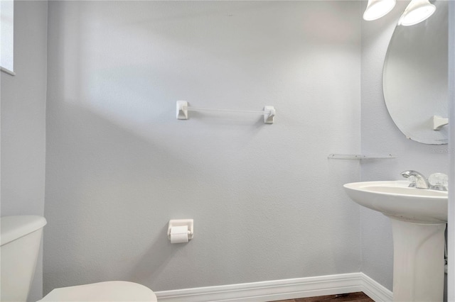 5768 Los Palma Vista Dr, Orlando, FL 32837 - half bathroom featuring toilet, a sink, baseboards, and wood finished floors