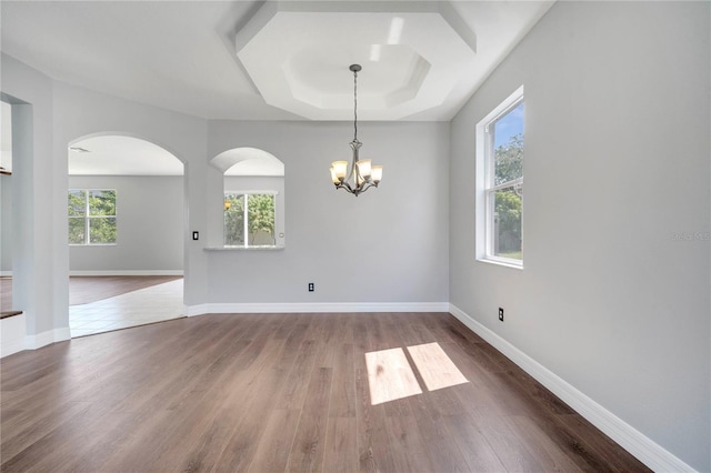 5768 Los Palma Vista Dr, Orlando, FL 32837 - empty room featuring arched walkways, wood finished floors, a tray ceiling, and a chandelier