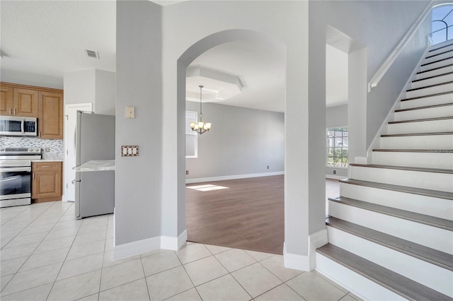 5768 Los Palma Vista Dr, Orlando, FL 32837 - stairs featuring a chandelier, baseboards, arched walkways, and tile patterned flooring