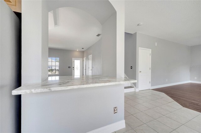 5768 Los Palma Vista Dr, Orlando, FL 32837 - kitchen with light tile patterned floors, baseboards, arched walkways, freestanding refrigerator, and light stone counters