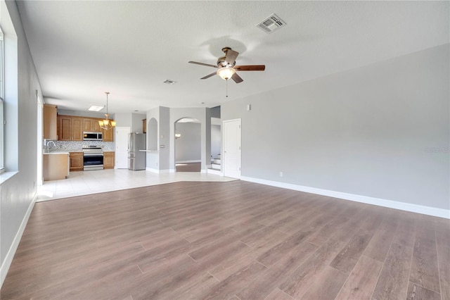 5768 Los Palma Vista Dr, Orlando, FL 32837 - unfurnished living room featuring ceiling fan, arched walkways, baseboards, light wood finished floors, and a sink