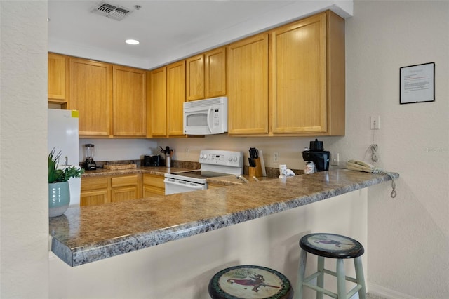 3060 Pirates Retreat Ct Unit 309, Kissimmee, FL 34747 - kitchen with white appliances, a textured wall, a peninsula, recessed lighting, and a kitchen bar