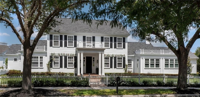 423 Arbor Cir, Celebration, FL 34747 - colonial house with a fenced front yard, a shingled roof, and a balcony
