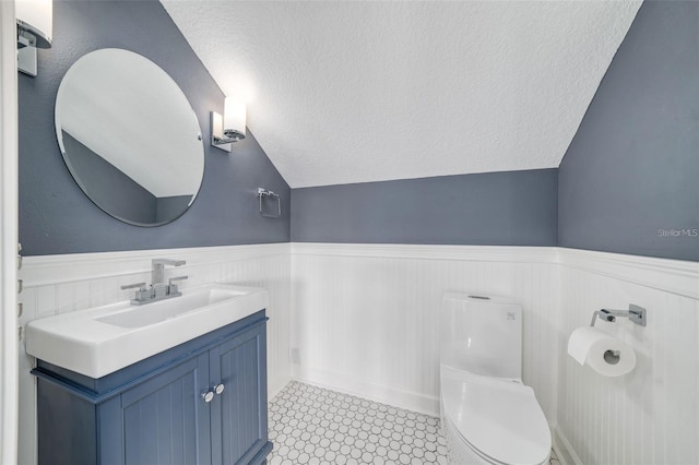 423 Arbor Cir, Celebration, FL 34747 - bathroom featuring wainscoting, lofted ceiling, toilet, a textured ceiling, and vanity