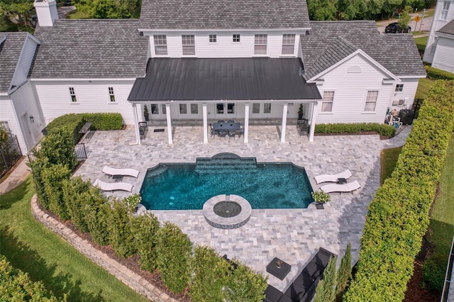 423 Arbor Cir, Celebration, FL 34747 - back of property with a patio, metal roof, a pool with connected hot tub, and a fire pit