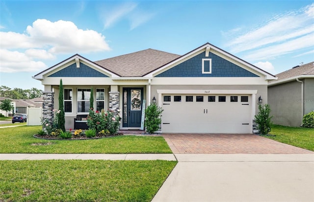 craftsman-style home featuring decorative driveway, a front lawn, an attached garage, and stucco siding