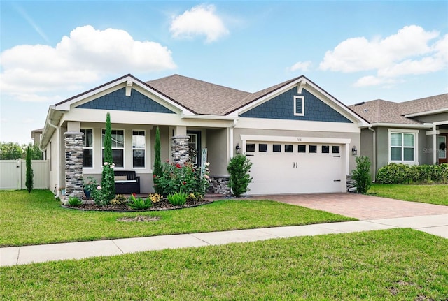 craftsman inspired home with decorative driveway, a garage, stucco siding, covered porch, and stone siding